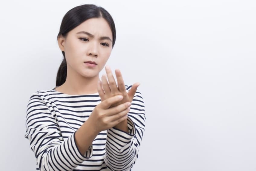 Mujer masajeándose los dedos y la mano para aumentar el flujo sanguíneo